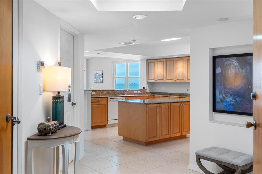 A view from a hallway into a kitchen with wood cabinets and a granite island — 16326 GULF BOULEVARD UNIT 510, REDINGTON BEACH, FL