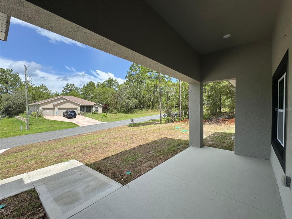 A covered concrete patio overlooks a grassy yard and a neighboring house across the street — 7687 N QUIBBLE AVENUE, DUNNELLON, FL