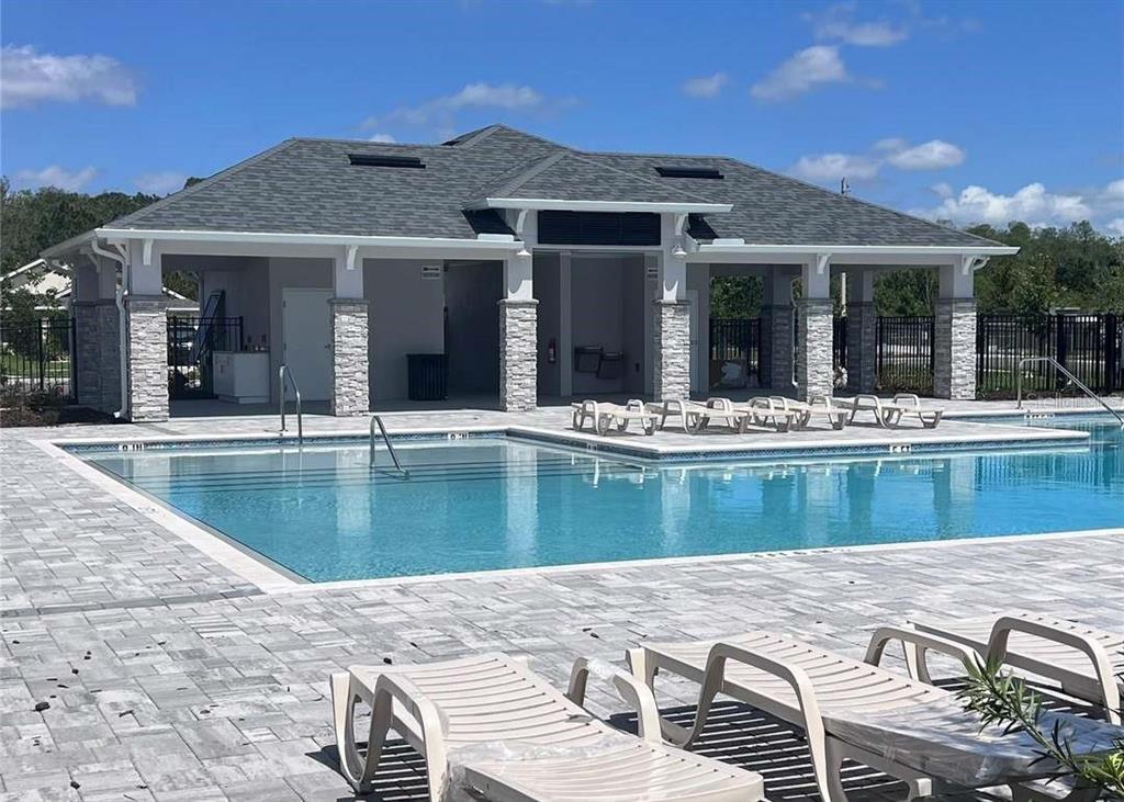 A swimming pool sits in front of a covered pavilion with stone-accented columns — 3756 SAGEFIELD DR, ST CLOUD, FL