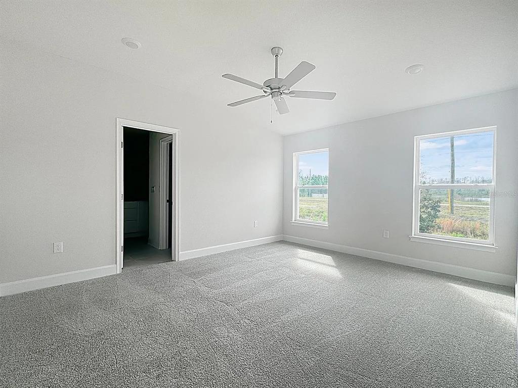 A bedroom with gray carpet, white walls, a ceiling fan, and two windows — 3756 SAGEFIELD DR, ST CLOUD, FL