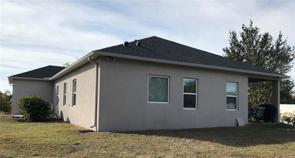 The exterior of a single-story house with a gray stucco finish and a dark roof — 15079 WICHITA ROAD, PORT CHARLOTTE, FL