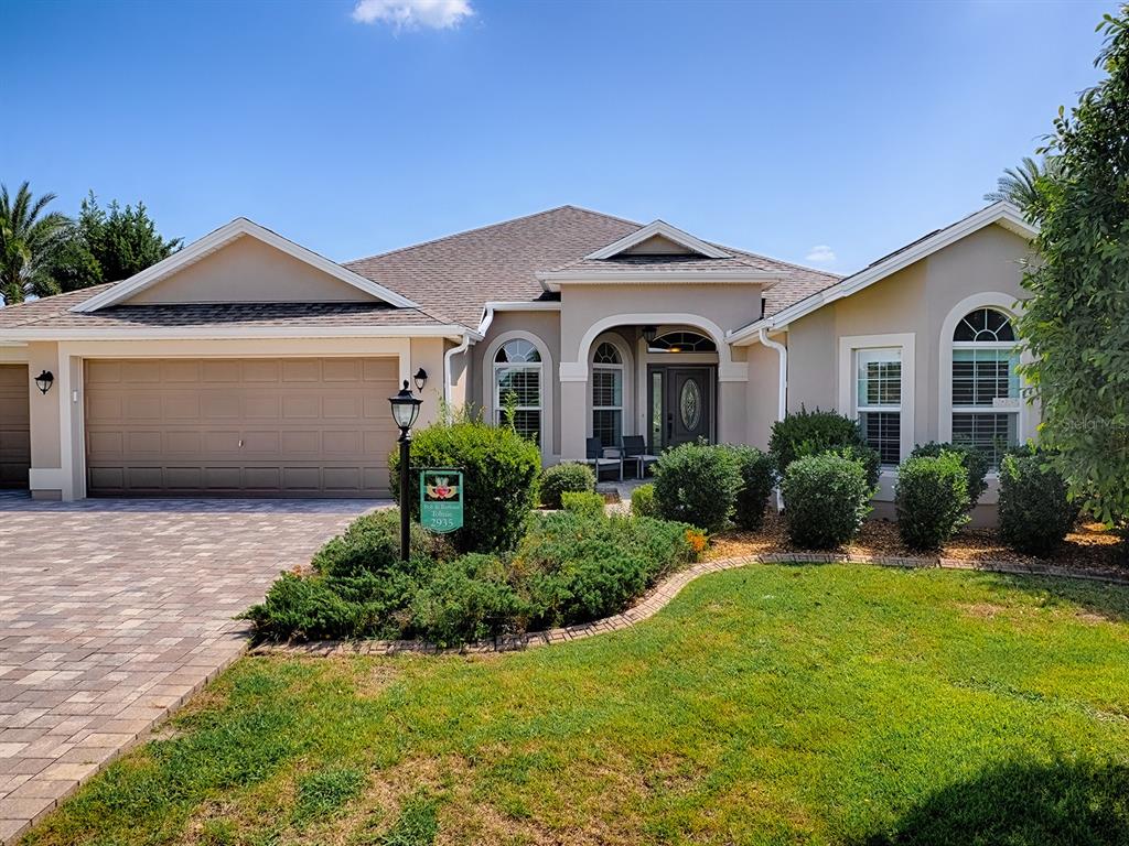 A single-story house with a beige stucco exterior, a paved driveway, and a landscaped yard — 2935 LURAVILLE ROAD, THE VILLAGES, FL