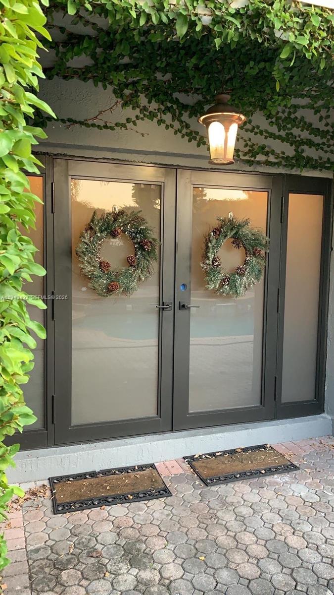 A pair of glass-paneled double doors with wreaths and a lantern light on a patio — 15448 SW 92nd St, Miami FL 33196, MIAMI, FL