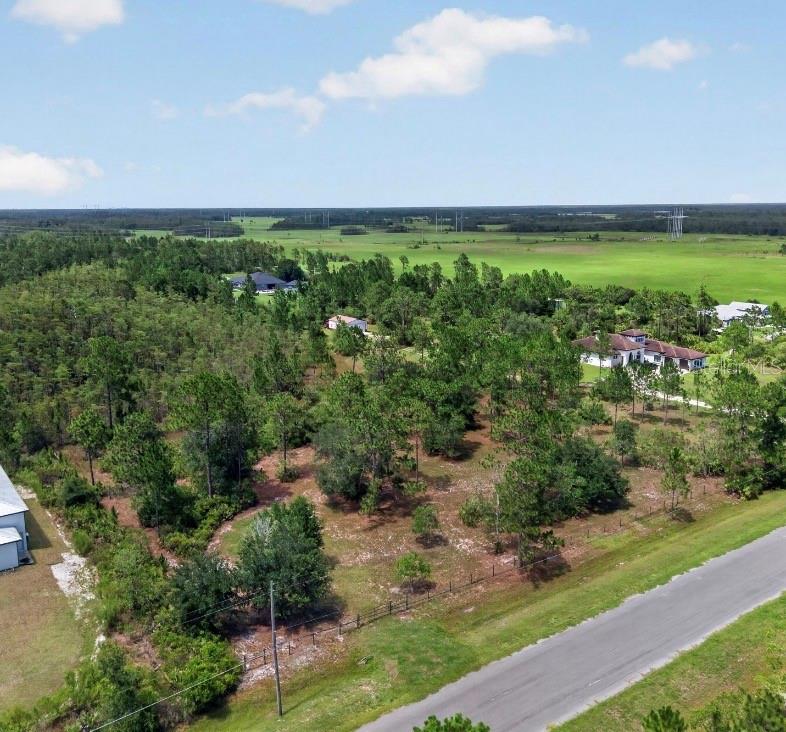 An aerial view shows a wooded lot next to a road with nearby residential houses — 20829 QUARTERLY PARKWAY, ORLANDO, FL