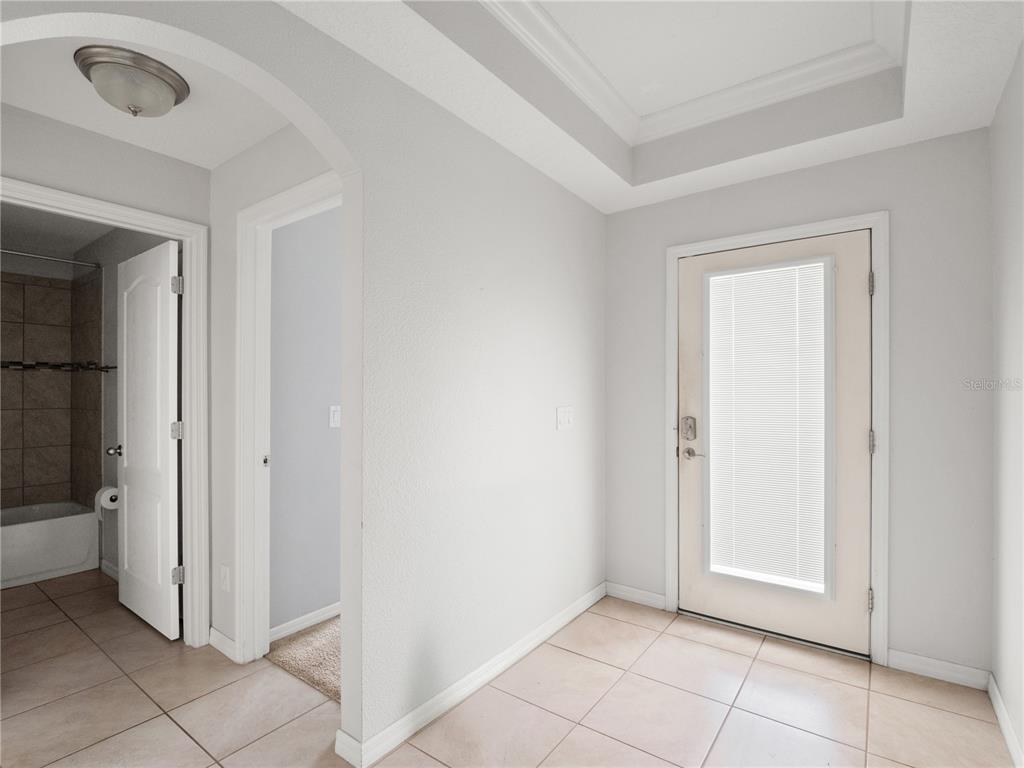 A tiled entryway features an arched doorway to a bathroom and a glass-paneled exterior door — 411 MILLWOOD PLACE, WINTER GARDEN, FL