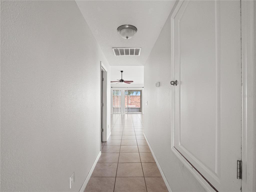 A tiled hallway leads to a living area with a ceiling fan and sliding glass doors — 411 MILLWOOD PLACE, WINTER GARDEN, FL
