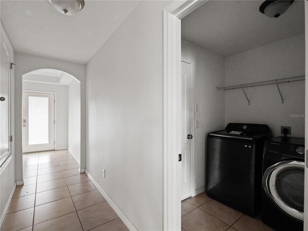 A tiled hallway leads to an exterior door, with a laundry room visible to the right — 411 MILLWOOD PLACE, WINTER GARDEN, FL