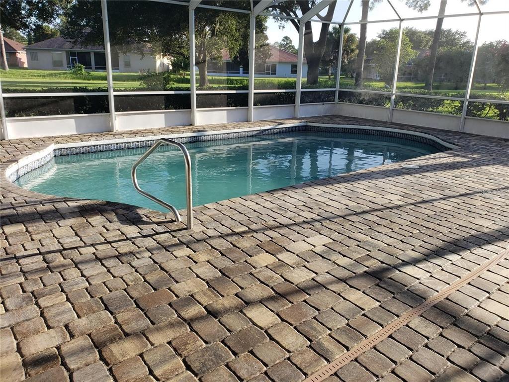 A swimming pool with a metal handrail is enclosed by a screened lanai with pavers — 9 MOUNT VERNON LANE, PALM COAST, FL