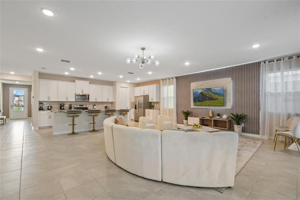 An open-concept kitchen and living room featuring white cabinetry, a curved sofa, and tile flooring — 8905 COCONUT BREEZE DRIVE, KISSIMMEE, FL