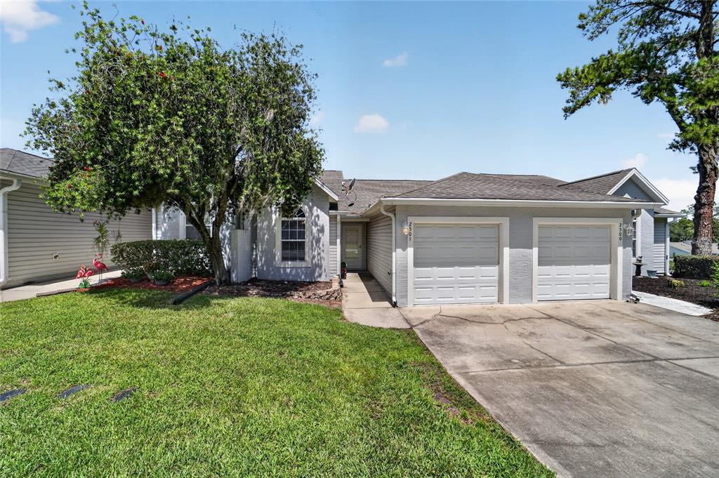 A single-story house with a two-car garage, a concrete driveway, and a large front tree — 2501 SE 18TH CIRCLE, OCALA, FL