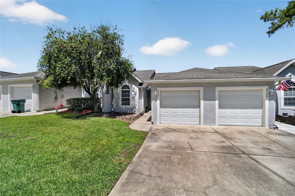 The exterior of a single-story house features a two-car garage and a large tree — 2501 SE 18TH CIRCLE, OCALA, FL