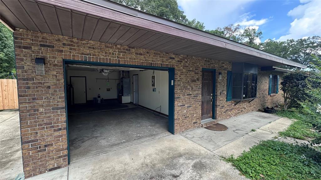 A brick house exterior features an open garage, a front door, and a bay window — 3315 NE 31ST AVENUE, OCALA, FL