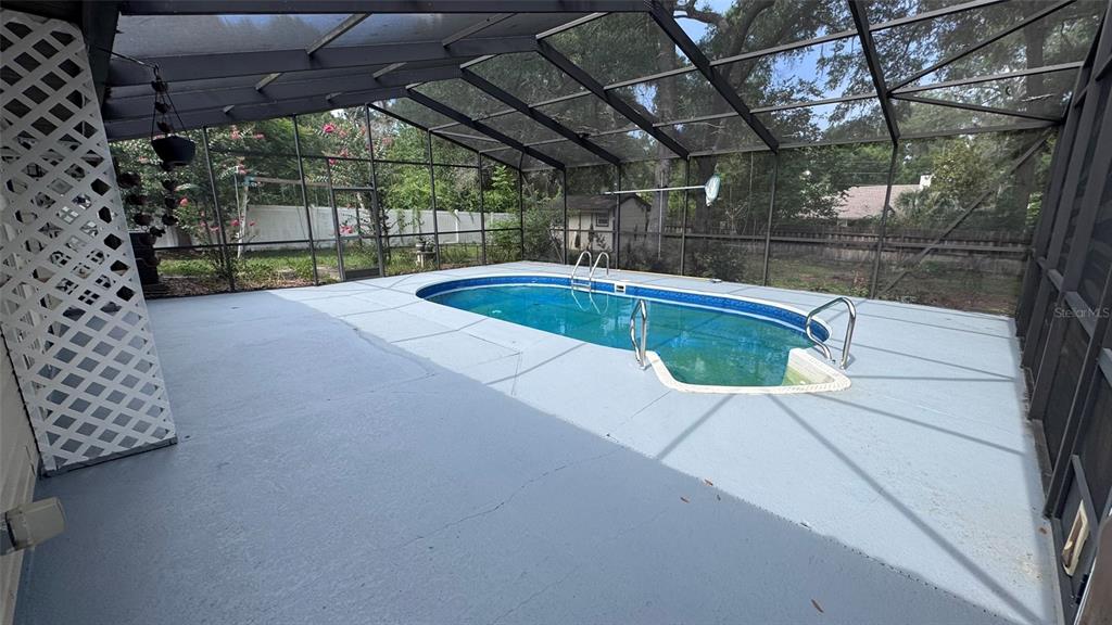 An enclosed swimming pool area with a concrete deck and a white lattice privacy screen — 3315 NE 31ST AVENUE, OCALA, FL