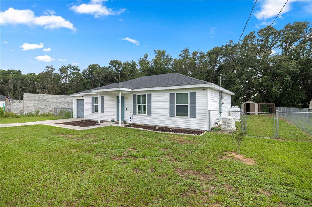 A white, single-story house with gray shutters and a fenced yard under a blue sky — 94 WILLOW ROAD, OCALA, FL