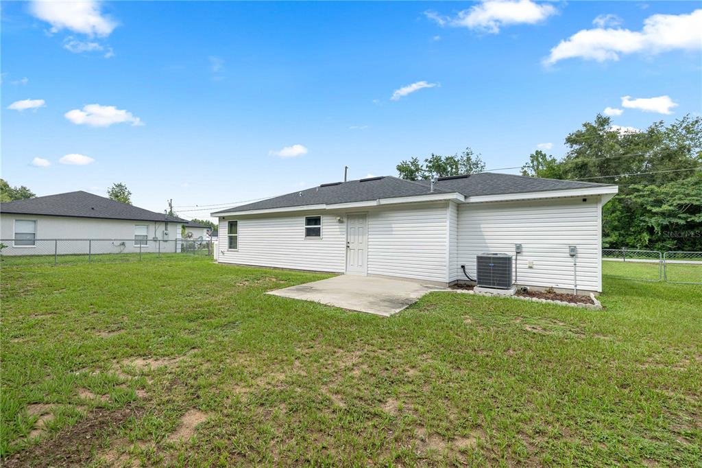The exterior of a white house features a small concrete patio and a backyard lawn — 94 WILLOW ROAD, OCALA, FL