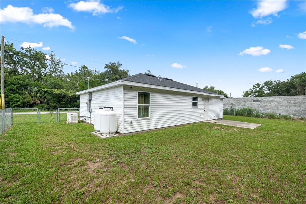 A white, single-story house with a hip roof, propane tanks, and a grassy backyard — 94 WILLOW ROAD, OCALA, FL