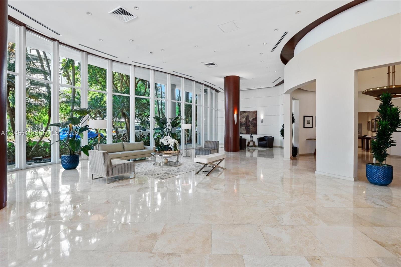 A spacious lobby features floor-to-ceiling windows, marble flooring, and a large central support column — 2475 Brickell Ave # 1805, Miami FL 33129, MIAMI, FL