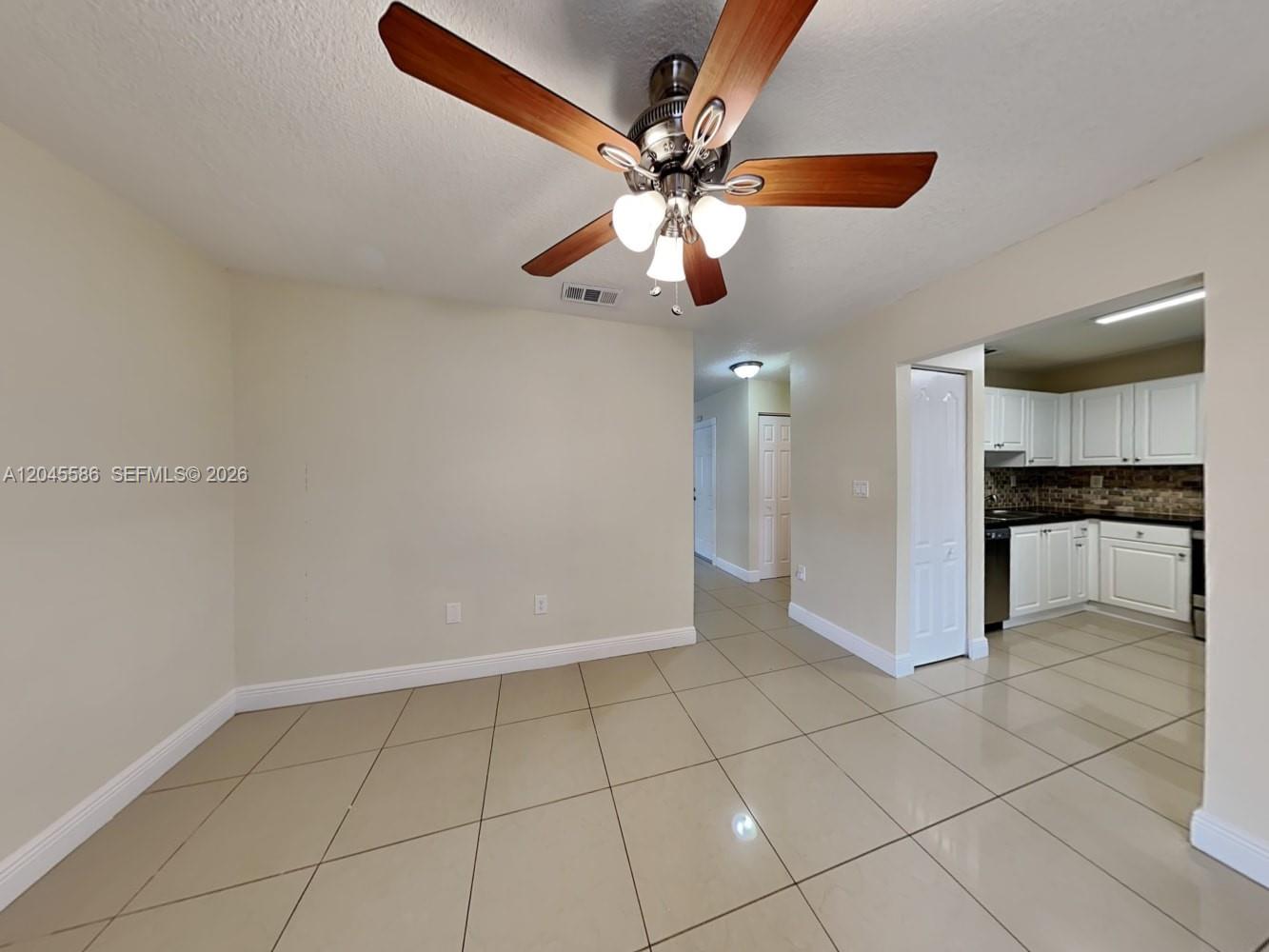 A dining area with beige tile floors, a ceiling fan, and an adjacent kitchen — MIAMI, FL