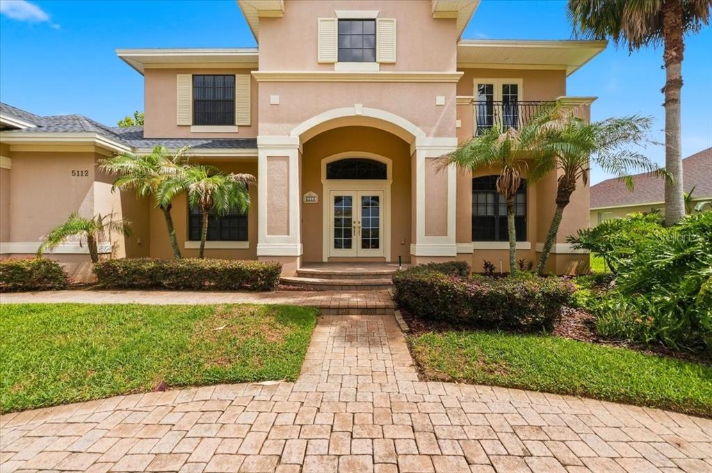 A two-story stucco house with a paved walkway, palm trees, and a double front door — 5112 HIGHLANDS LAKEVIEW LOOP, LAKELAND, FL