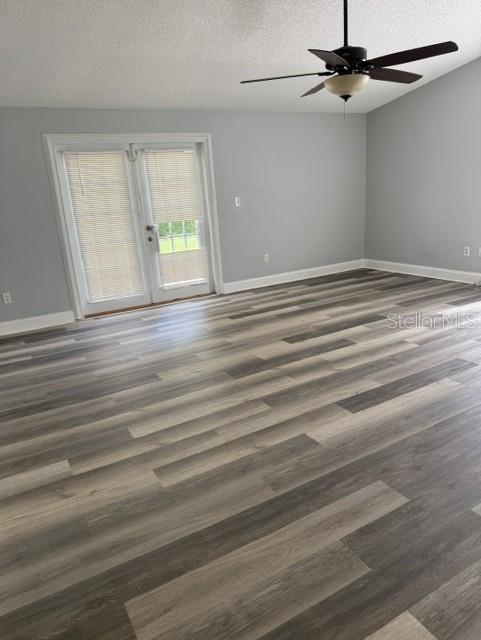 An empty room features light gray walls, wood-look plank flooring, a ceiling fan, and French doors — 2857 CINNAMON BEAR TRAIL, PALM HARBOR, FL