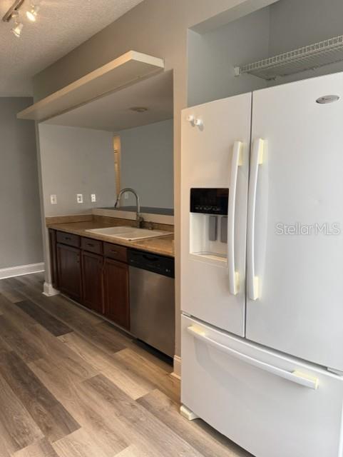 A kitchen features dark wood cabinets, a stainless steel dishwasher, and a white refrigerator — 2857 CINNAMON BEAR TRAIL, PALM HARBOR, FL