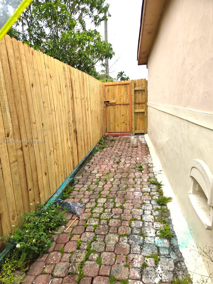 A narrow side yard features a brick walkway, a wooden fence, and a gate — 4610 SW 40th St # 1, West Park FL 33023, WEST PARK, FL