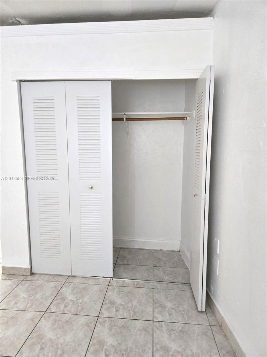A white closet with louvered doors and a single shelf stands on tiled flooring — 4610 SW 40th St # 1, West Park FL 33023, WEST PARK, FL