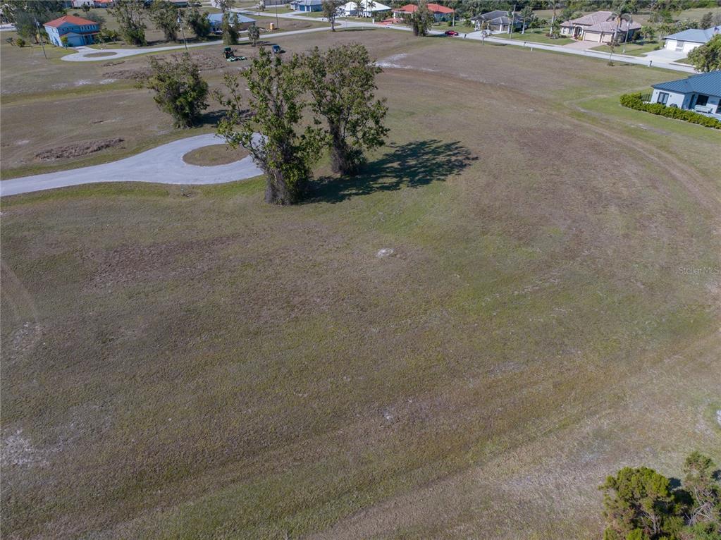 An aerial view shows a large, grassy vacant lot with two prominent trees — 17154 SUGAR COURT, PUNTA GORDA, FL