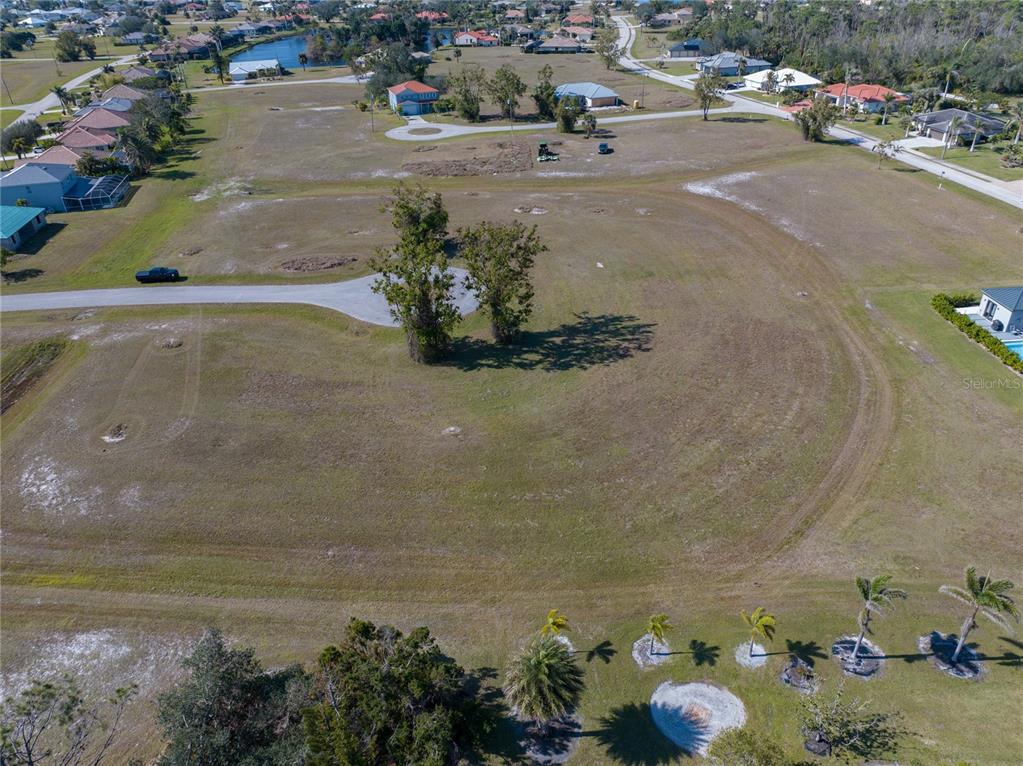An aerial view shows a large, vacant residential lot with two trees and surrounding houses — 17154 SUGAR COURT, PUNTA GORDA, FL