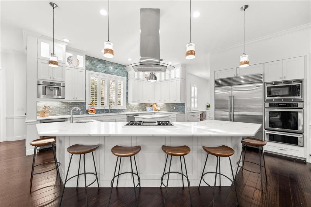 A modern kitchen features a large white marble island, stainless steel appliances, and pendant lighting — 6413 MACLAURIN DRIVE, TAMPA, FL