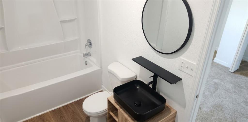 A bathroom features a white tub, a black vessel sink, and a round black mirror — 1412 LAUREL STREET, PALATKA, FL