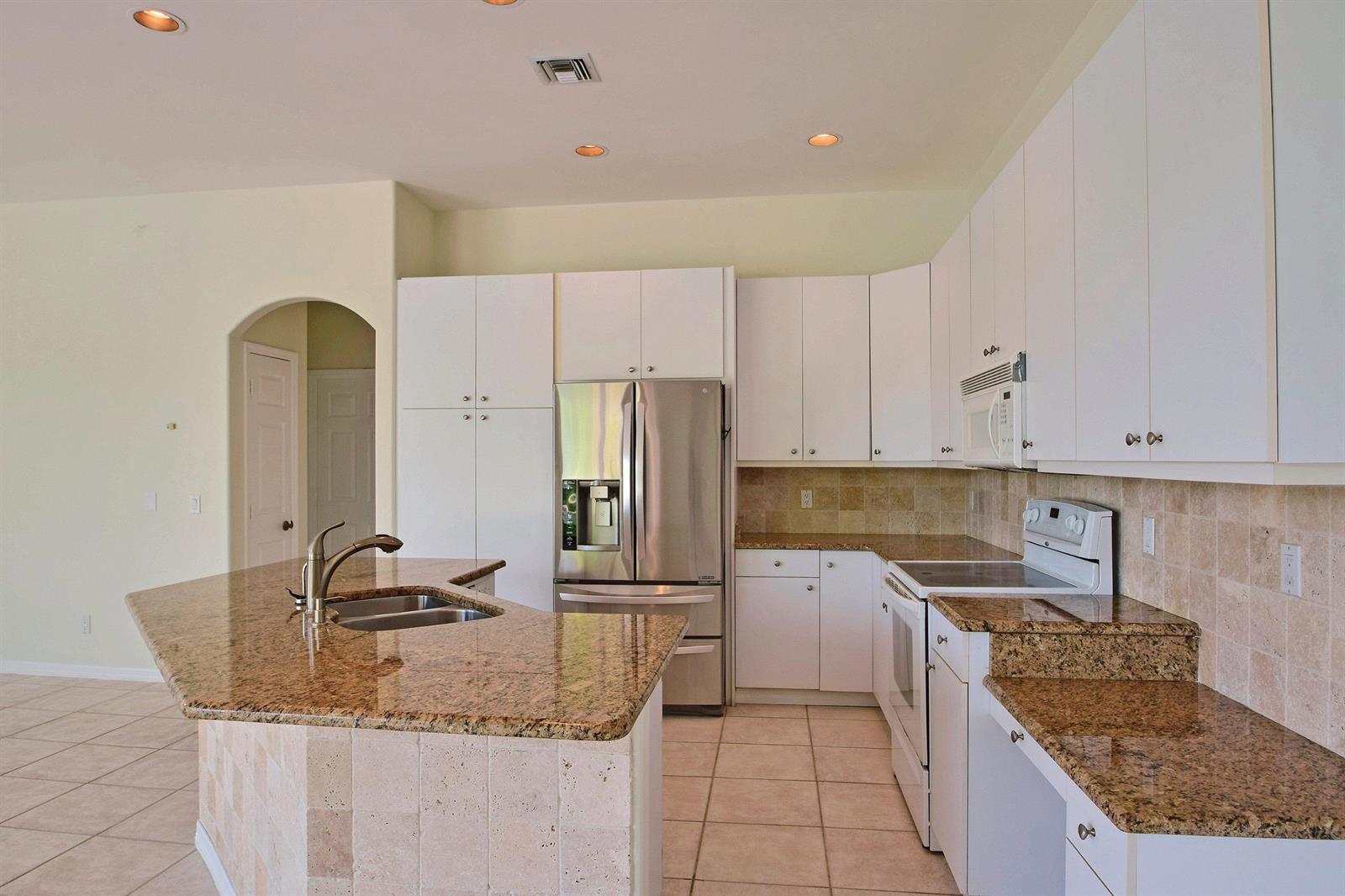 A kitchen features white cabinets, granite countertops, stainless steel appliances, and a tiled island — 705 Bahia Mar Road, FL, FL