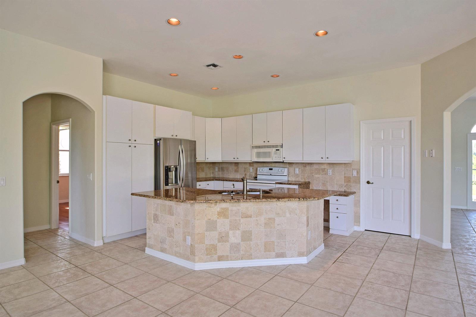 A kitchen features white cabinets, granite countertops, a tiled island, and light-colored floor tiles — 705 Bahia Mar Road, FL, FL