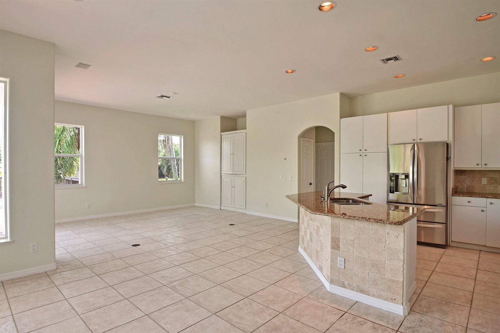 A kitchen with granite countertops and white cabinets opens into a large, tiled living area — 705 Bahia Mar Road, FL, FL