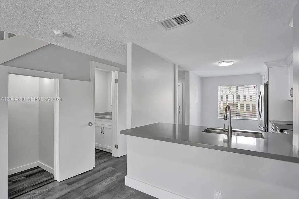 A kitchen features a gray countertop, white cabinets, and a view into a hallway — 5084 S University Dr, Davie FL 33328, DAVIE, FL