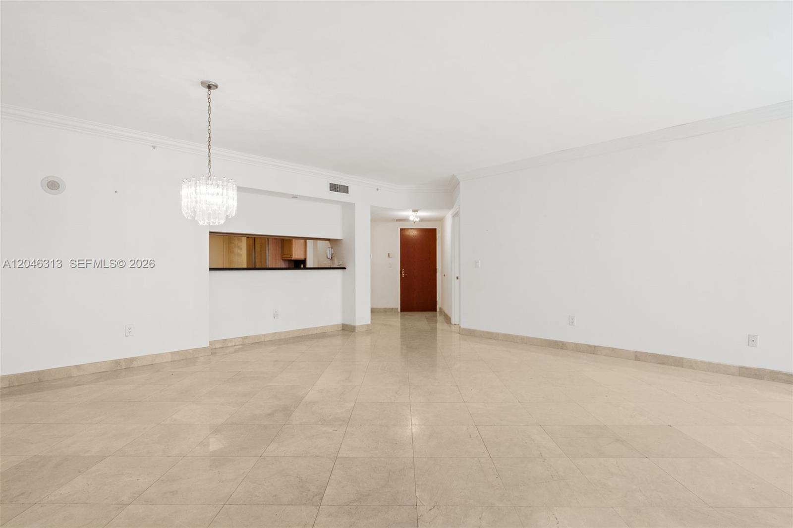 An empty room features white walls, light-colored tile flooring, a crystal chandelier, and large windows — 9595 Collins Ave # D, Surfside FL 33154, SURFSIDE, FL