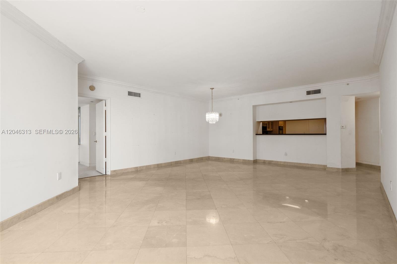 An empty room features beige tile flooring, white walls, and a crystal chandelier — 9595 Collins Ave # D, Surfside FL 33154, SURFSIDE, FL