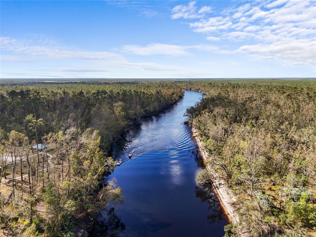 An aerial view shows a river flowing through a dense forest with two small boats — TBD WILDWOOD DRIVE, LIVE OAK, FL