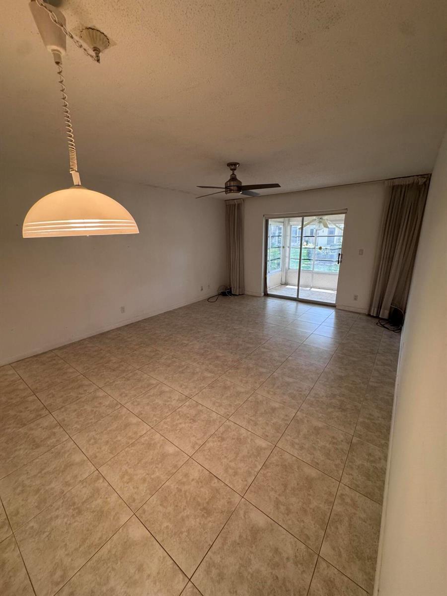 A spacious room with beige tile flooring, a ceiling fan, and sliding glass doors — 5660 SW 3rd Place # 105, Margate FL 33068, MARGATE, FL
