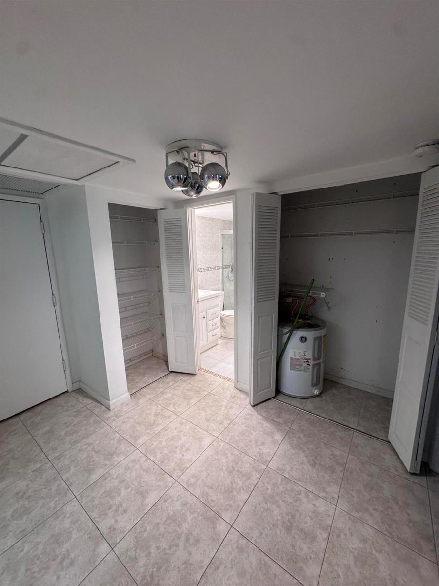 A tiled room features two open closets, one containing a water heater, and a bathroom entrance — 5660 SW 3rd Place # 105, Margate FL 33068, MARGATE, FL