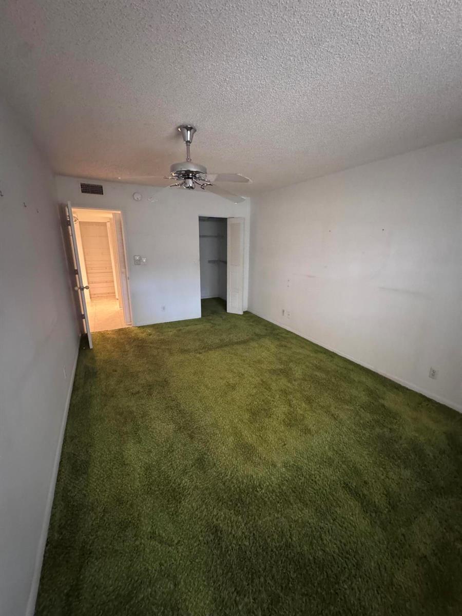 An empty bedroom features bright green wall-to-wall carpeting, white walls, and a ceiling fan — 5660 SW 3rd Place # 105, Margate FL 33068, MARGATE, FL