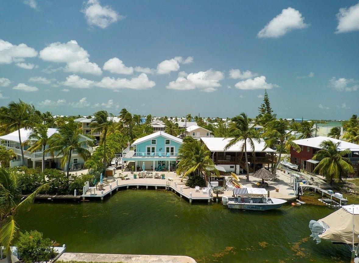 An aerial view of a waterfront house with a deck, boat dock, and palm trees — 28525 Jolly Roger Drive, FL 33042, FL