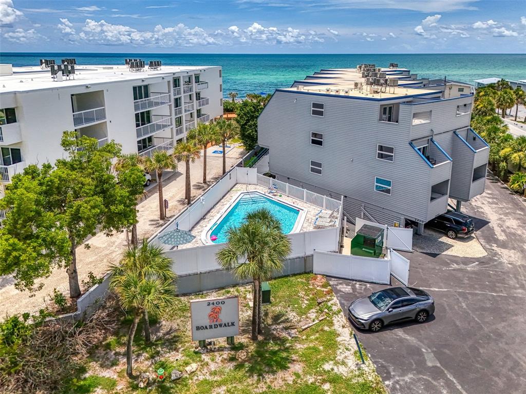 An aerial view shows two multi-story apartment buildings with a central pool and parking area — 2400 N BEACH ROAD UNIT 17, ENGLEWOOD, FL