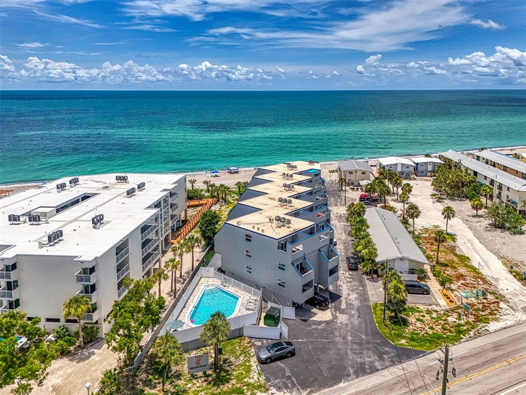 An aerial view shows a beachfront apartment complex with a swimming pool and parking area — 2400 N BEACH ROAD UNIT 17, ENGLEWOOD, FL