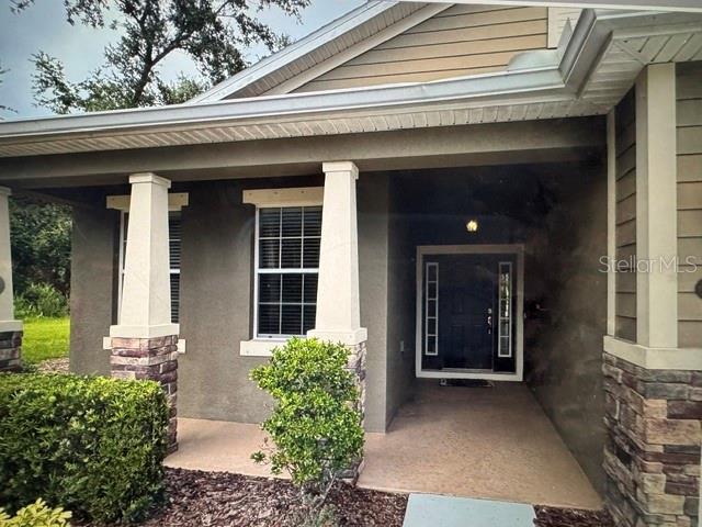 The exterior of a house features a screened-in porch, a paver patio, and palm trees — 8302 KARPEAL DRIVE, SARASOTA, FL
