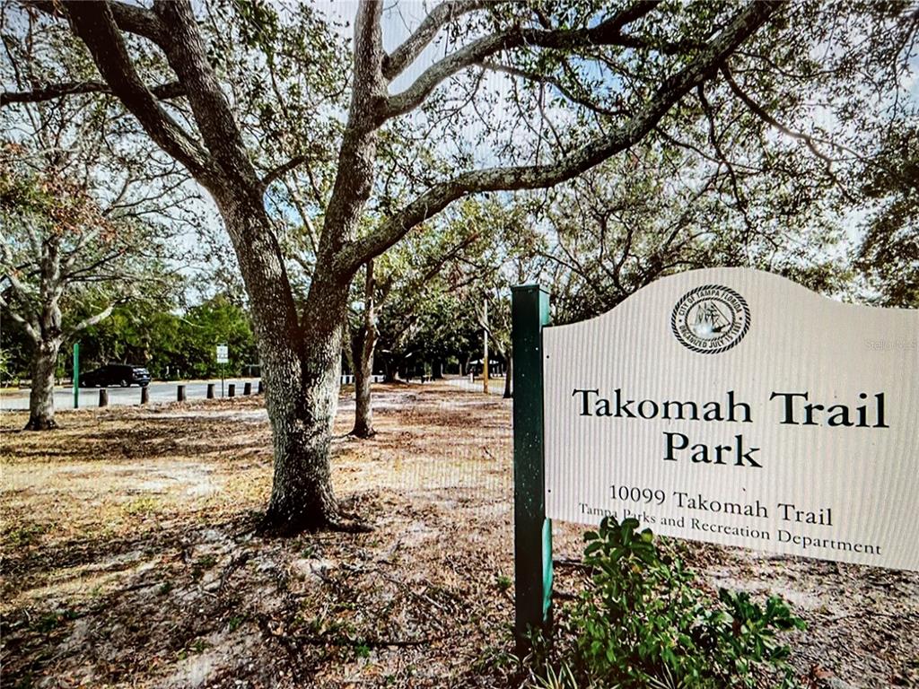 A sign for Takomah Trail Park stands in front of a wooded area with trees — 10201 TAKOMAH TRAIL, TAMPA, FL