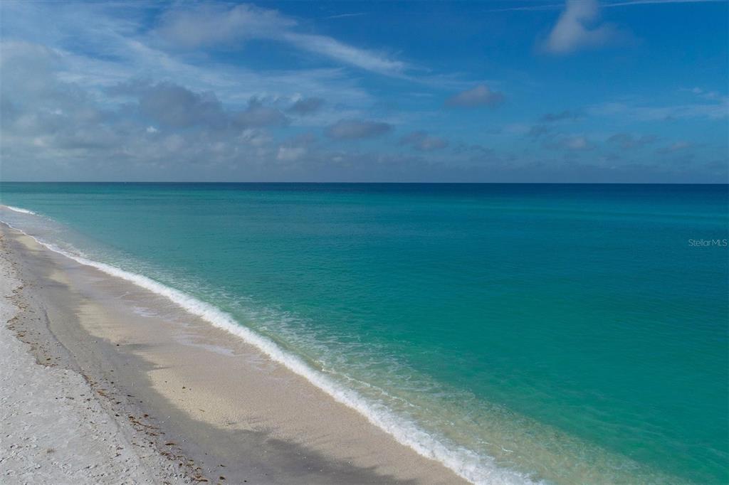 An aerial view of a sandy beach meeting the turquoise ocean under a blue sky — 10201 TAKOMAH TRAIL, TAMPA, FL