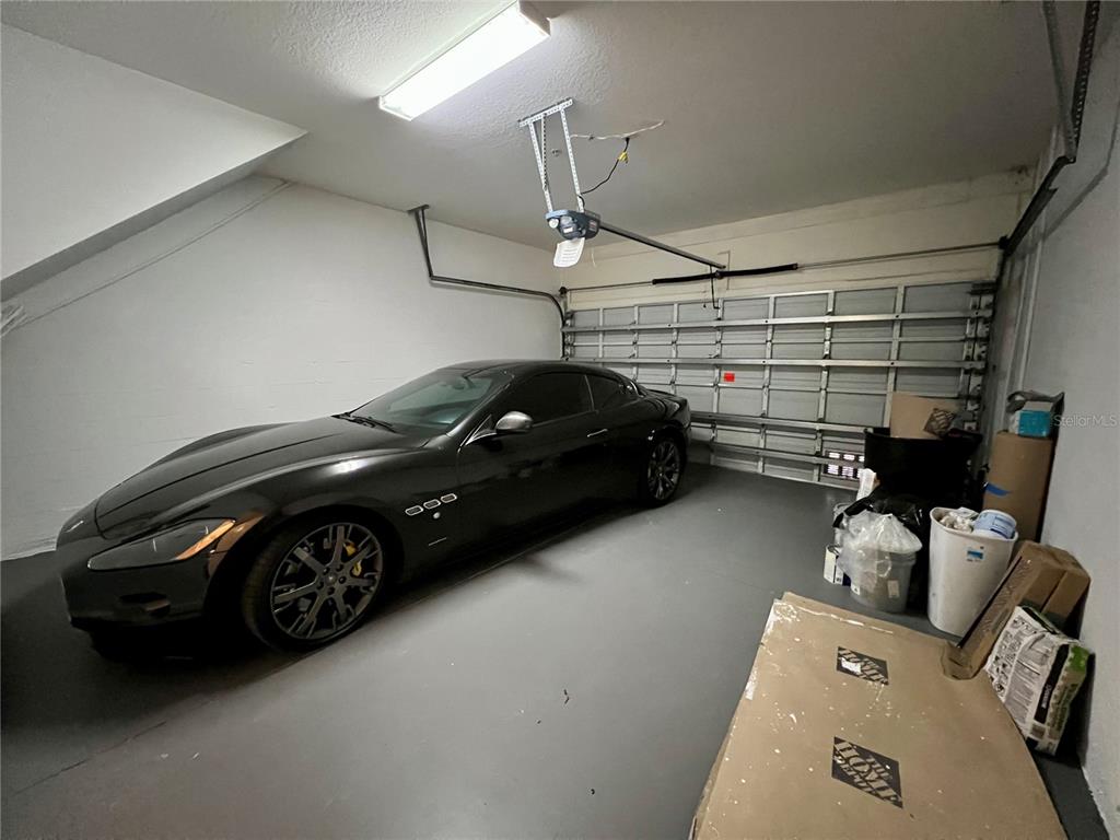 A dark sports car is parked inside a garage with a concrete floor — 809 HARBOR OAK LANE, CLEARWATER, FL