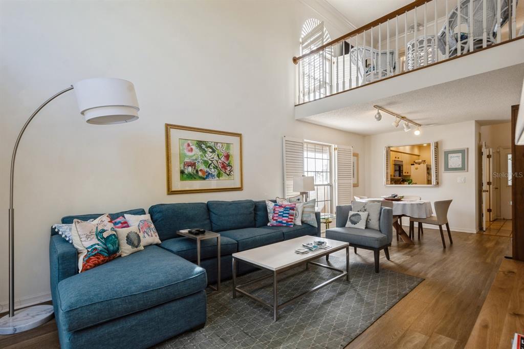 A living room with a blue sectional sofa, coffee table, and a lofted balcony above — 1195 COQUILLE STREET UNIT 309, SARASOTA, FL