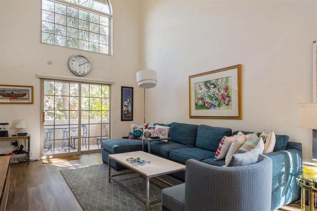 A living room features a blue sectional sofa, a coffee table, and a sliding glass door — 1195 COQUILLE STREET UNIT 309, SARASOTA, FL